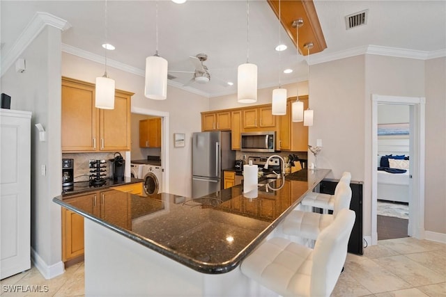 kitchen with hanging light fixtures, a kitchen breakfast bar, kitchen peninsula, decorative backsplash, and appliances with stainless steel finishes