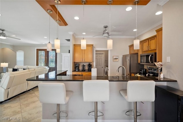 kitchen with pendant lighting, a kitchen breakfast bar, crown molding, ceiling fan, and appliances with stainless steel finishes