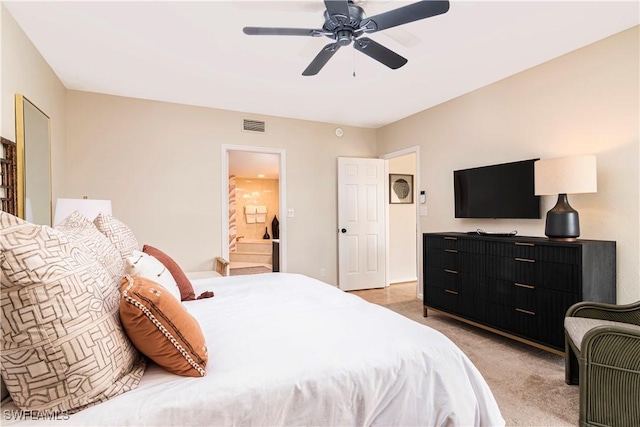 bedroom with light colored carpet, ceiling fan, and ensuite bath