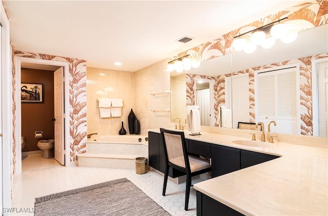 bathroom featuring toilet, vanity, a bathtub, and a bidet