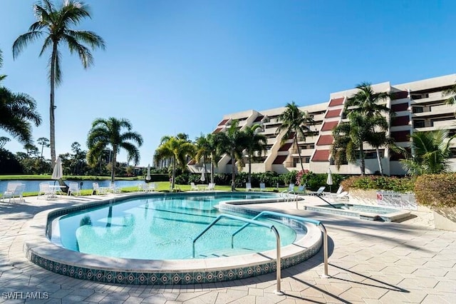 view of pool featuring a water view, a hot tub, and a patio