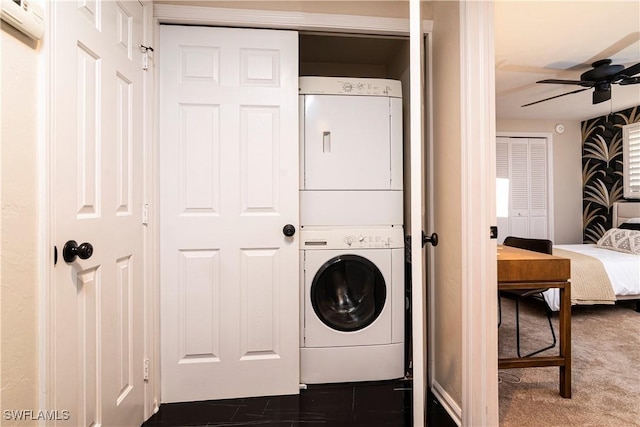 washroom with dark carpet, ceiling fan, and stacked washer / dryer