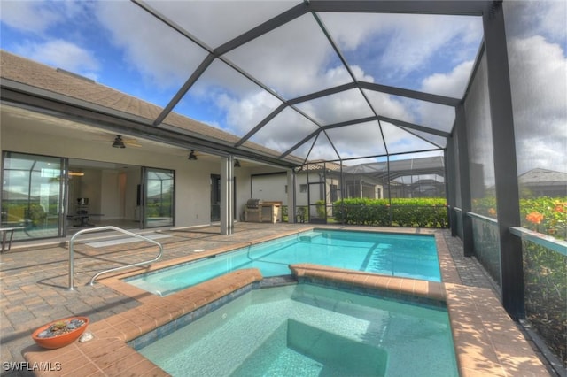 view of swimming pool with an in ground hot tub, a patio, glass enclosure, and ceiling fan