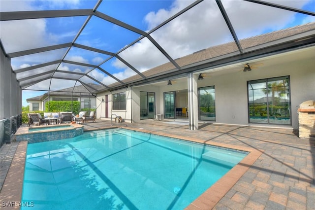 view of pool featuring glass enclosure, ceiling fan, a patio area, and an in ground hot tub