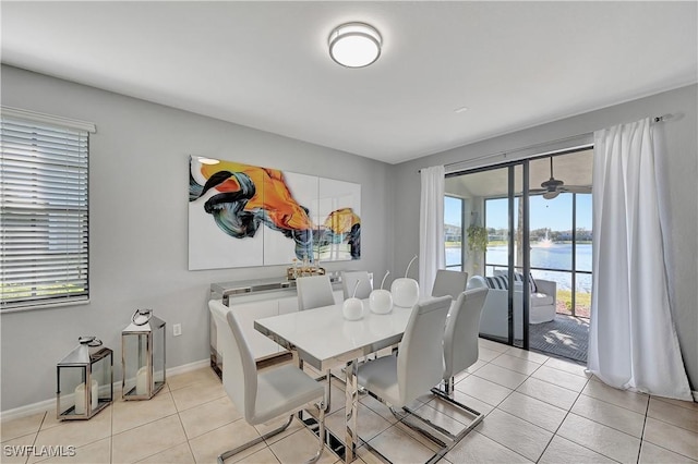 tiled dining area featuring a water view and ceiling fan