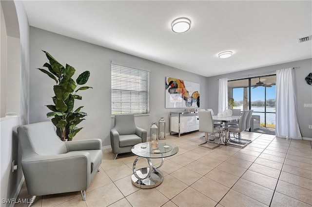 tiled living room with ceiling fan and a water view