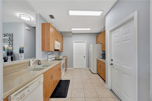 kitchen with light tile patterned flooring, white appliances, and sink