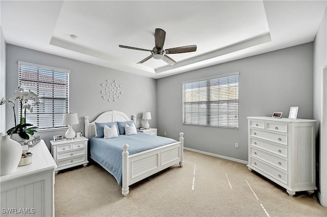 bedroom with ceiling fan, a raised ceiling, and light colored carpet