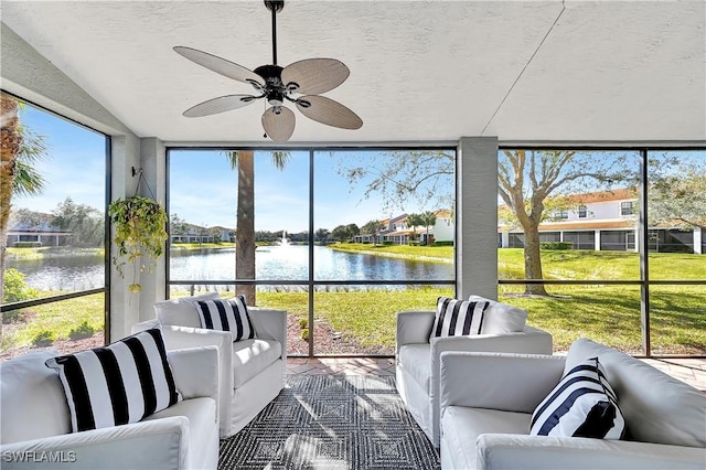 sunroom with ceiling fan and a water view