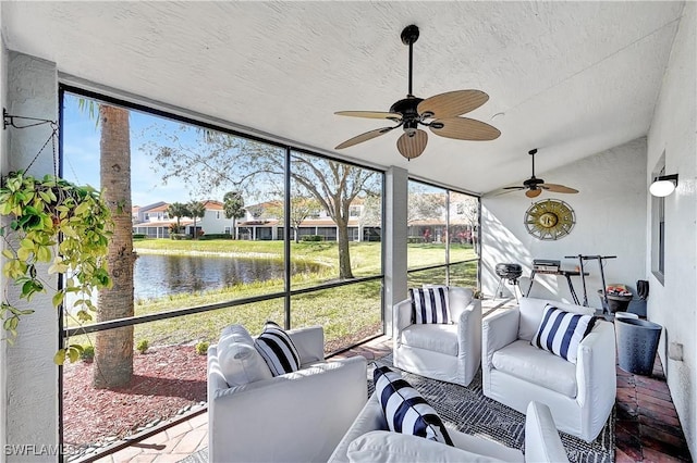 sunroom with a wealth of natural light, a water view, lofted ceiling, and ceiling fan