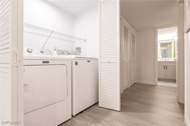 clothes washing area featuring light wood-type flooring and washer and clothes dryer