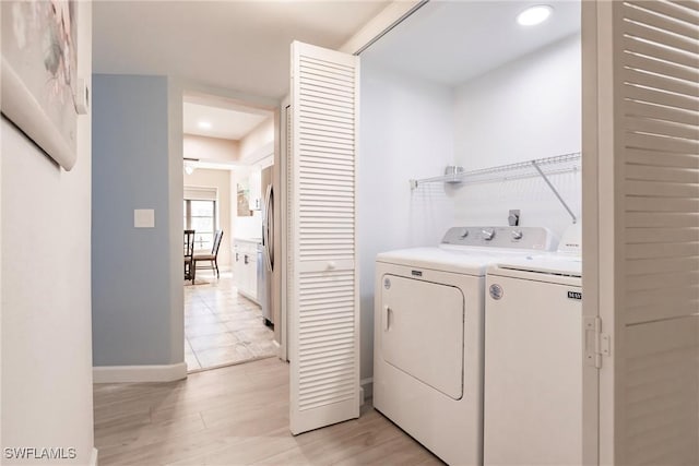 clothes washing area featuring washing machine and dryer and light hardwood / wood-style floors