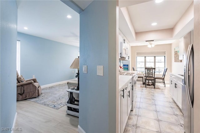 kitchen featuring a raised ceiling, white range with electric cooktop, and white cabinets