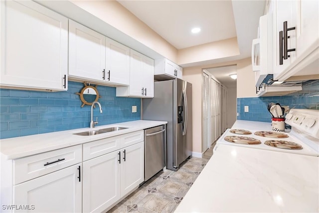 kitchen with light stone countertops, sink, backsplash, white cabinets, and appliances with stainless steel finishes