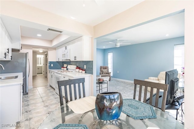 kitchen with ceiling fan, sink, backsplash, white appliances, and white cabinets