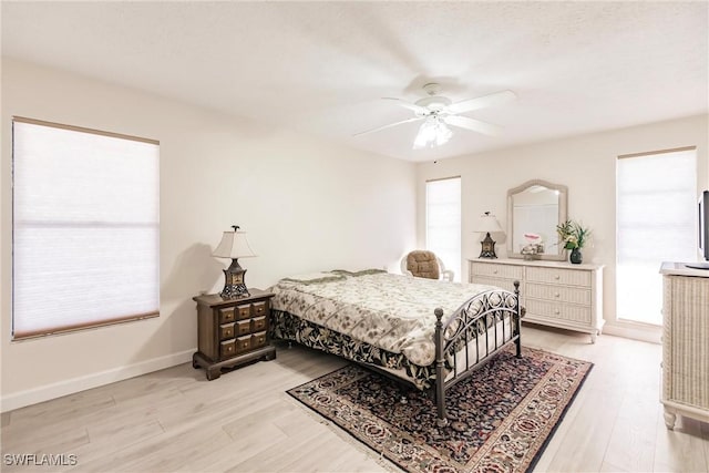 bedroom with multiple windows, ceiling fan, and light hardwood / wood-style floors