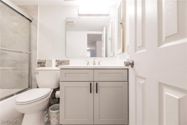 full bathroom featuring vanity, enclosed tub / shower combo, and toilet