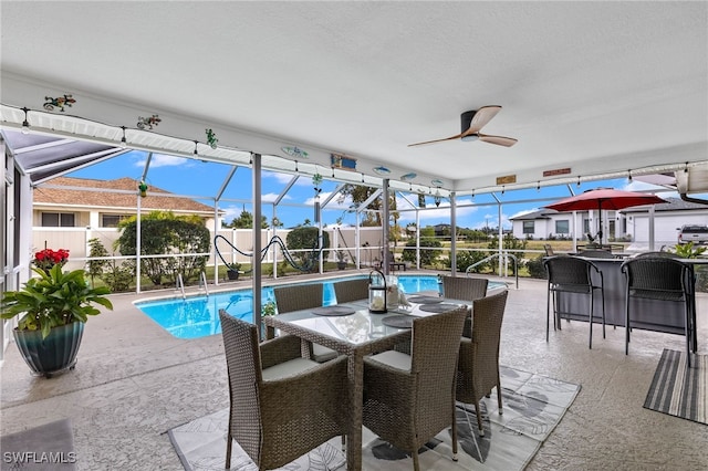 exterior space with ceiling fan, glass enclosure, and a patio