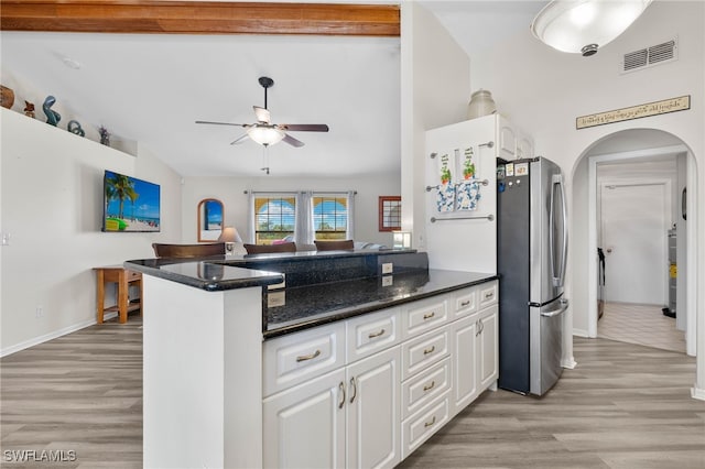 kitchen with stainless steel refrigerator, kitchen peninsula, lofted ceiling with beams, and white cabinets