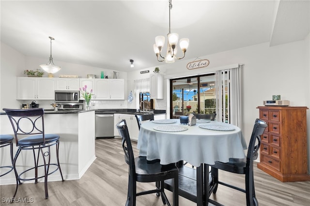 dining area featuring lofted ceiling, sink, a chandelier, and light hardwood / wood-style floors