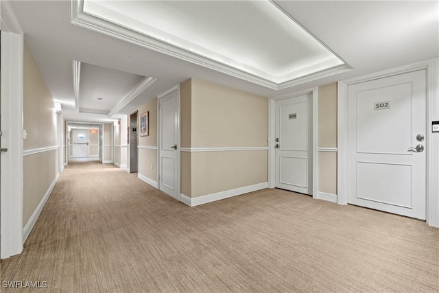 hallway with light colored carpet and a tray ceiling