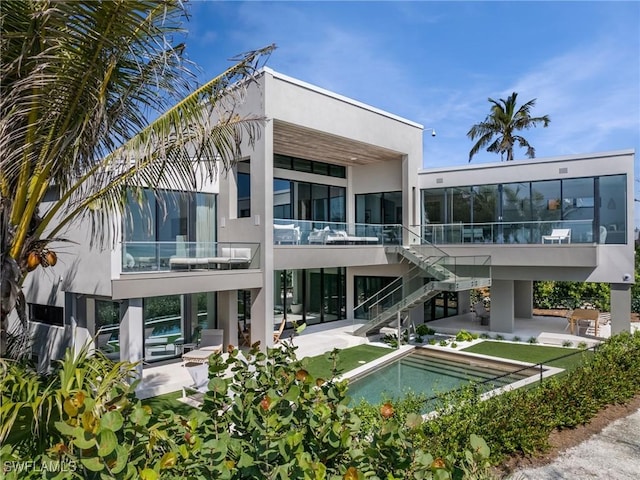 rear view of house featuring a patio area, a balcony, and a pool