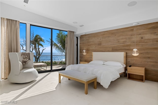 bedroom featuring access to exterior, a water view, and wooden walls