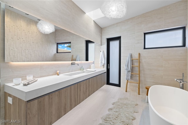 bathroom featuring wood-type flooring, vanity, tile walls, and a bathing tub