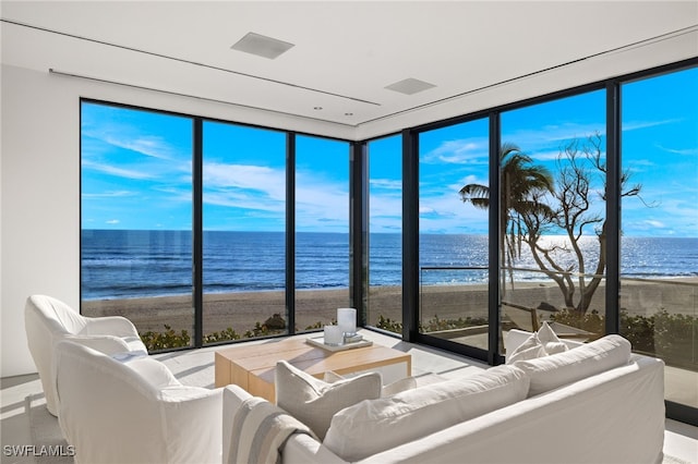 living room featuring plenty of natural light, floor to ceiling windows, a view of the beach, and a water view