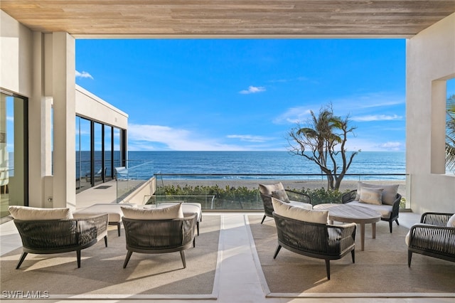 view of patio / terrace with an outdoor living space, a water view, and a beach view