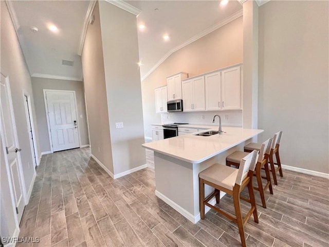 kitchen featuring sink, stainless steel appliances, kitchen peninsula, a breakfast bar, and white cabinets