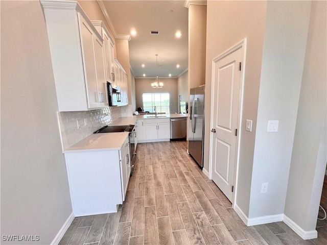 kitchen with sink, stainless steel appliances, backsplash, pendant lighting, and white cabinets