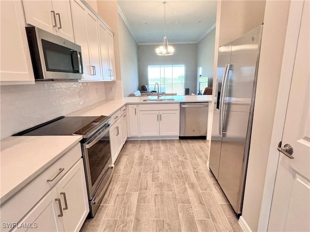 kitchen featuring appliances with stainless steel finishes, white cabinetry, pendant lighting, and sink