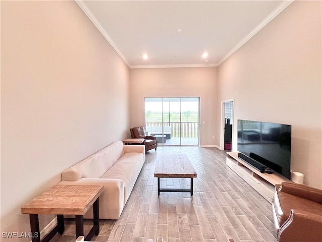 living room featuring light hardwood / wood-style flooring, a high ceiling, and ornamental molding