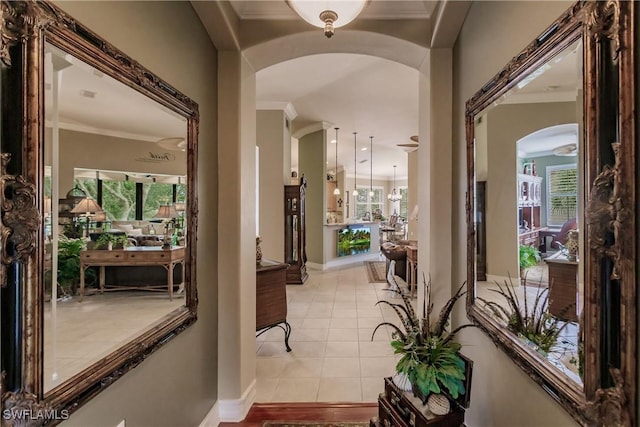 corridor featuring light tile patterned floors, a chandelier, and ornamental molding