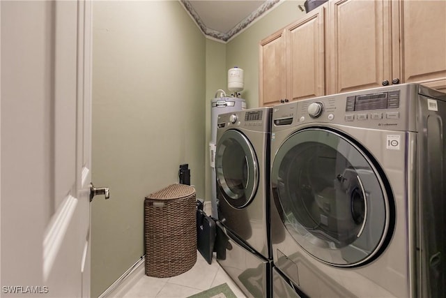 clothes washing area featuring light tile patterned floors, cabinet space, and washing machine and dryer