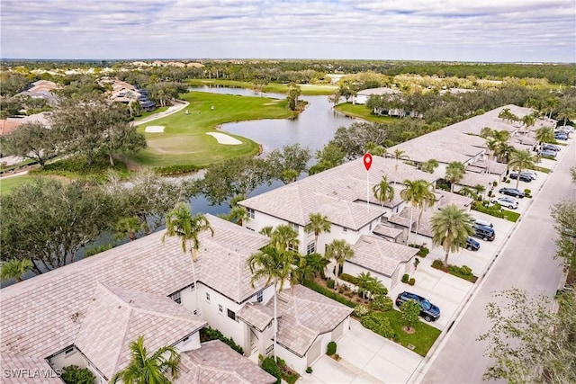 drone / aerial view featuring golf course view, a water view, and a residential view