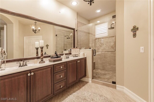 bathroom with an enclosed shower, vanity, and an inviting chandelier