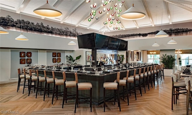 bar with light parquet floors, beamed ceiling, and hanging light fixtures