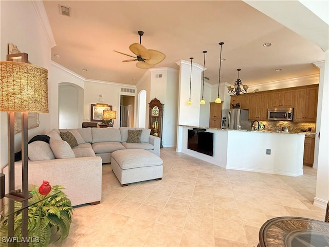 living area with visible vents, ornamental molding, light tile patterned floors, arched walkways, and a ceiling fan