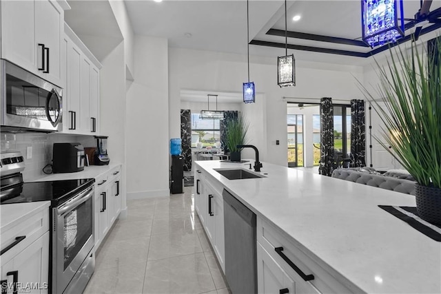 kitchen with appliances with stainless steel finishes, a raised ceiling, sink, pendant lighting, and white cabinetry