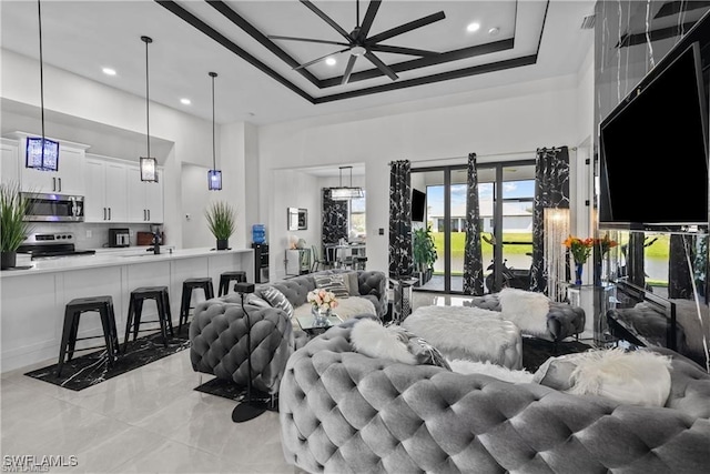 living room featuring a tray ceiling, ceiling fan, and a high ceiling