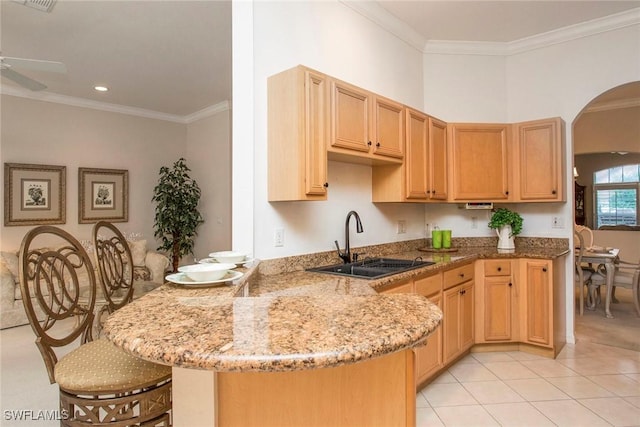 kitchen with ornamental molding, a kitchen breakfast bar, kitchen peninsula, and sink