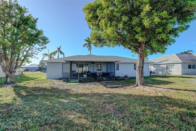 back of property with a lawn and a sunroom