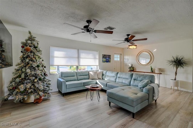 living room with ceiling fan, light hardwood / wood-style floors, and a textured ceiling