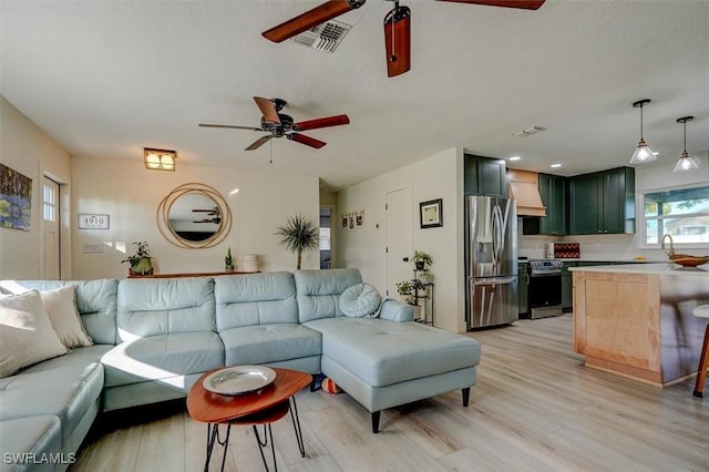 living room featuring light wood-type flooring, ceiling fan, and sink