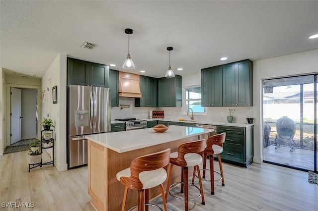 kitchen featuring a kitchen breakfast bar, sink, appliances with stainless steel finishes, a kitchen island, and custom range hood