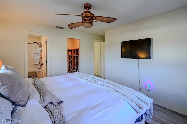 bedroom with ensuite bath, a spacious closet, ceiling fan, wood-type flooring, and a closet