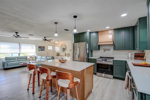 kitchen featuring light wood-type flooring, appliances with stainless steel finishes, backsplash, and custom range hood