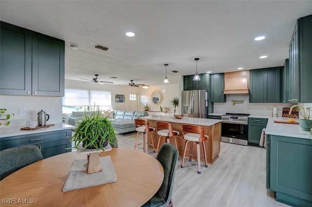 kitchen featuring appliances with stainless steel finishes, light wood-type flooring, sink, a kitchen island, and hanging light fixtures